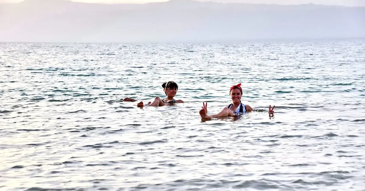 Two swimmers floating upright in the Dead Sea, the experience a Dead Sea hotel or resort is built around