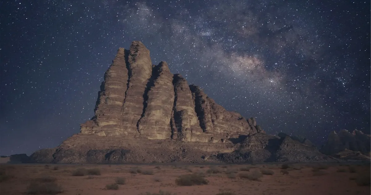 The Milky Way over a sandstone massif in Wadi Rum, seen from a dark desert camp