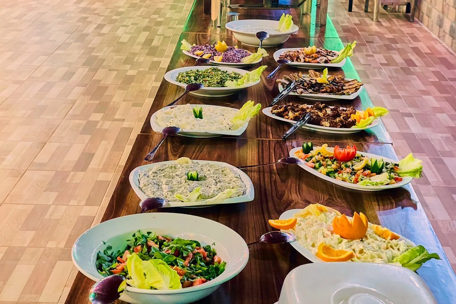A long table of mezze salads and rice laid out at a Bedouin camp