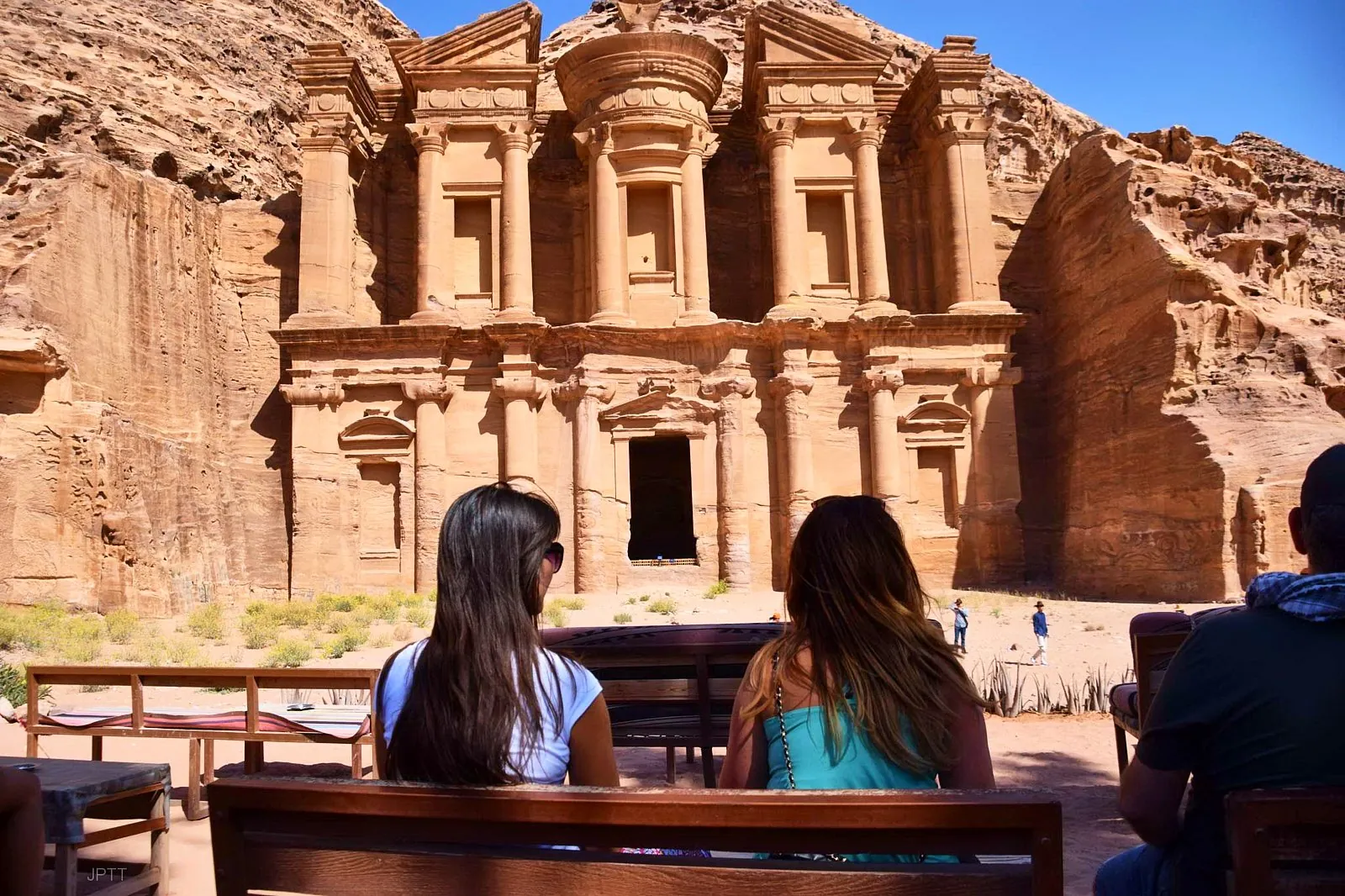 Visitors resting on a bench opposite the Monastery (Ad-Deir) at Petra
