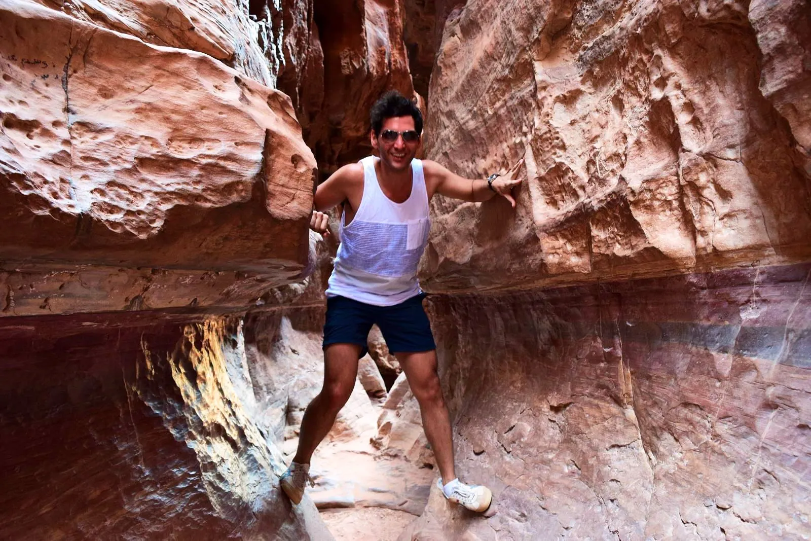 A walker in the narrow, banded sandstone corridor of Petra's Siq