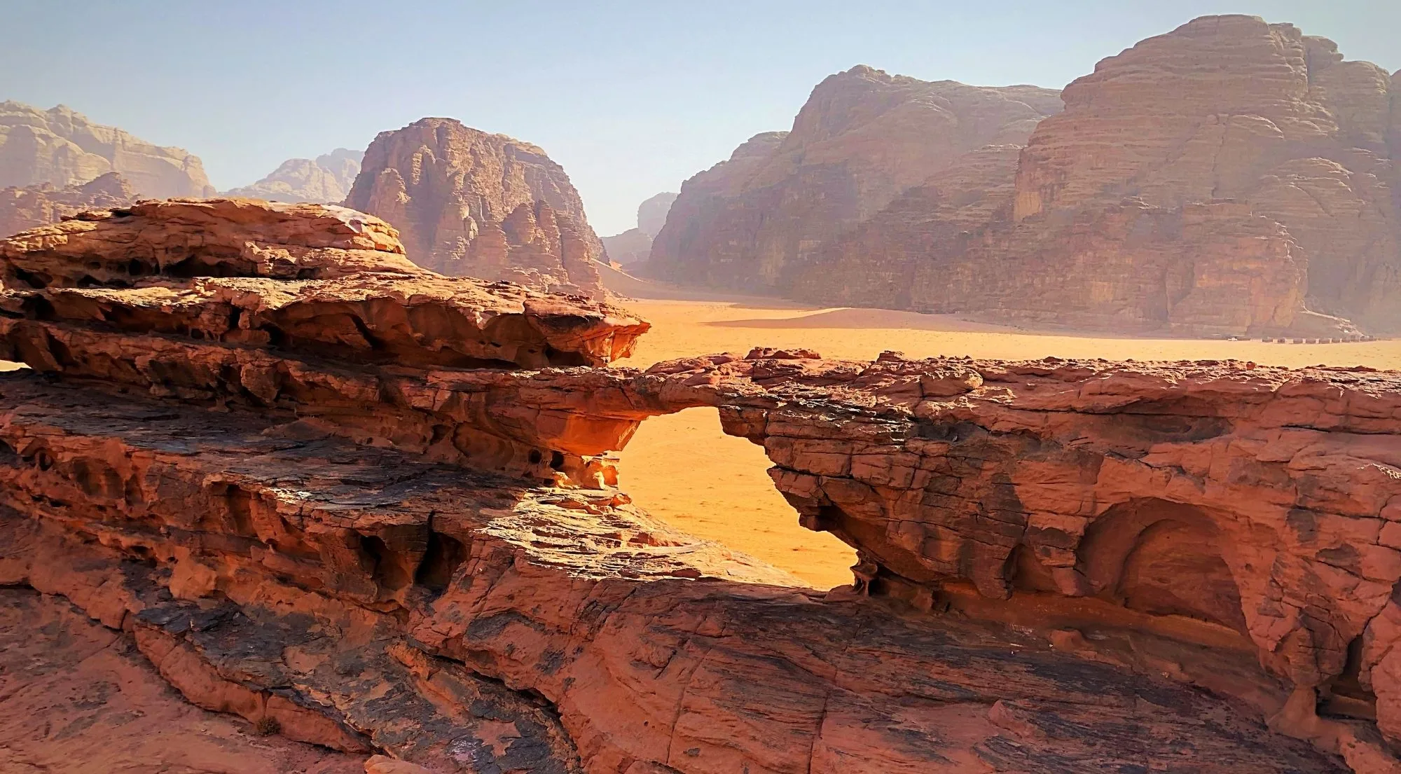 A natural rock arch above the open desert floor of Wadi Rum