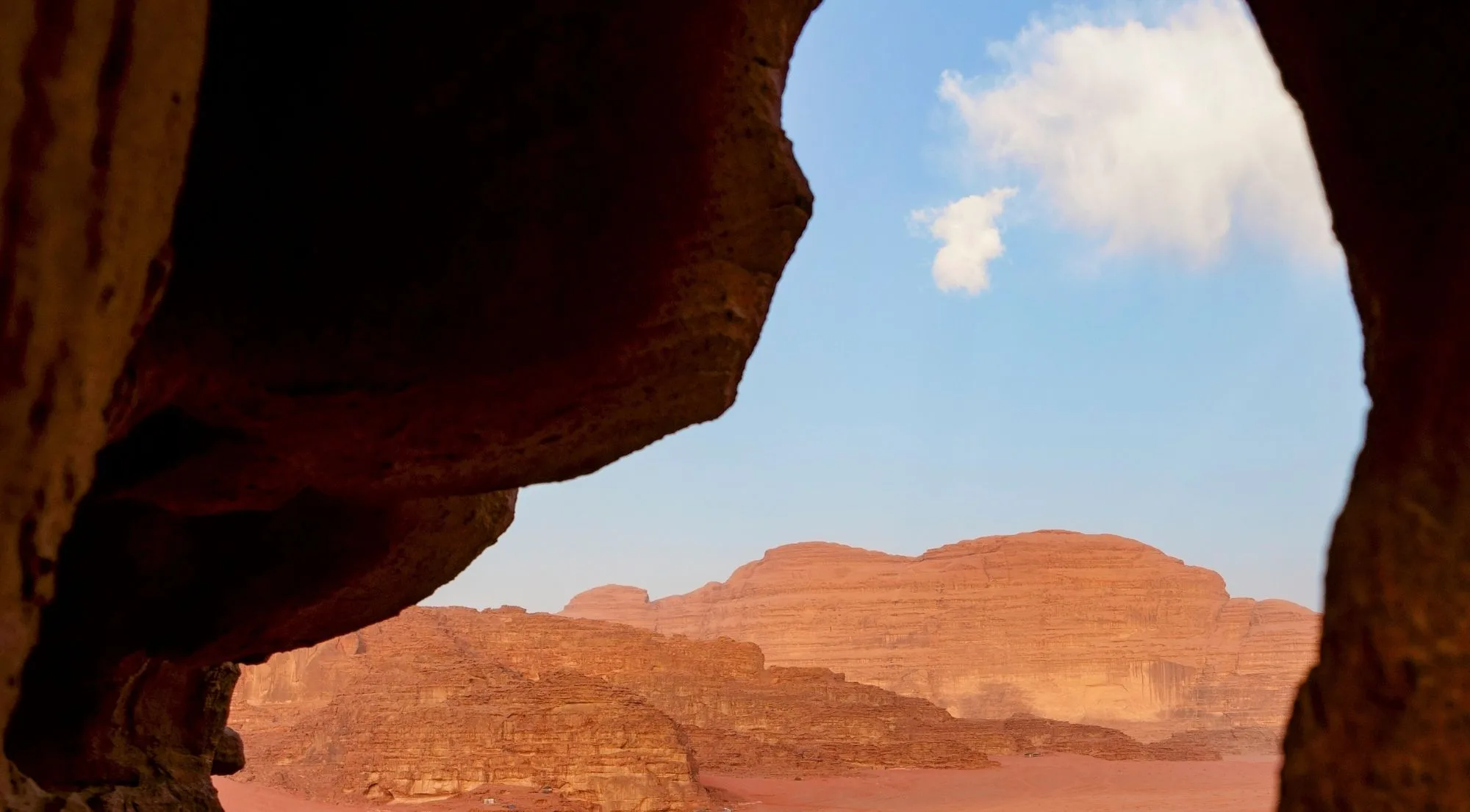 The view out of a rock overhang onto the Wadi Rum desert and sky