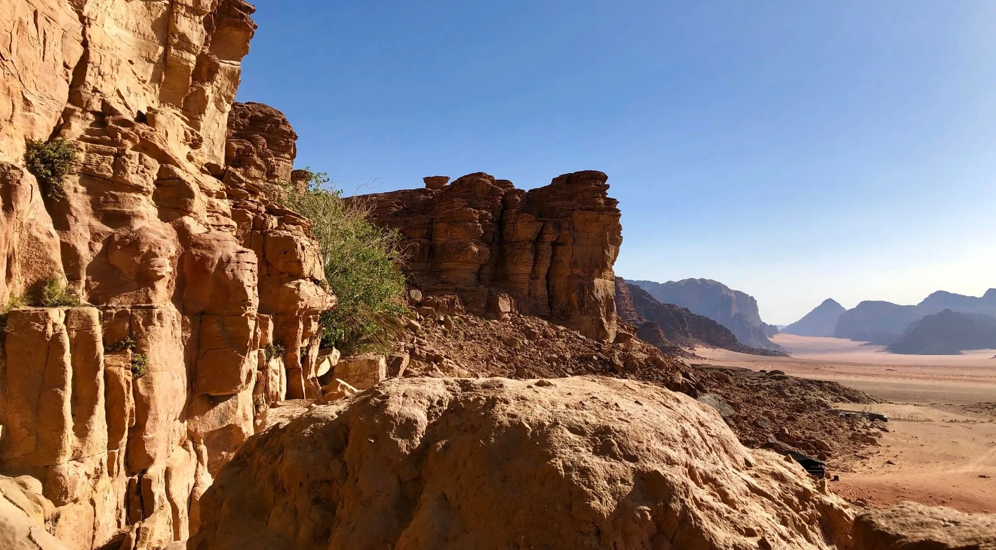A rocky outcrop looking out over the Wadi Rum plain under a clear sky